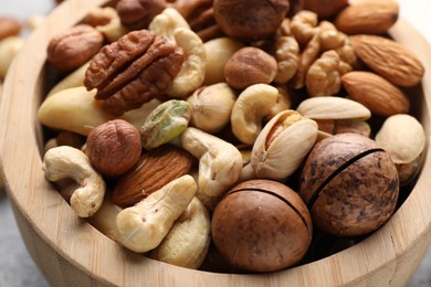 Photo of Mix of different nuts in bowl on table, closeup