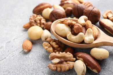 Photo of Mix of different nuts on grey textured table, closeup. Space for text