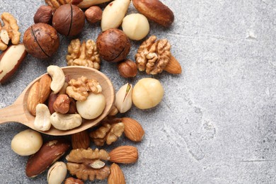 Photo of Mix of different nuts on grey textured table, above view. Space for text