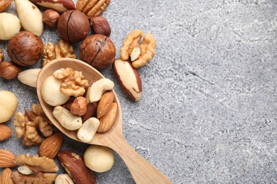 Photo of Mix of different nuts on grey textured table, above view. Space for text