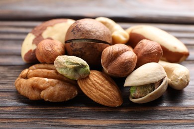 Photo of Mix of different nuts on wooden table, closeup