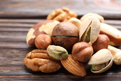 Photo of Mix of different nuts on wooden table, closeup