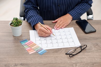 Photo of Woman using business planner at wooden desk, closeup