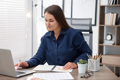 Photo of Woman with planner using laptop at desk in office