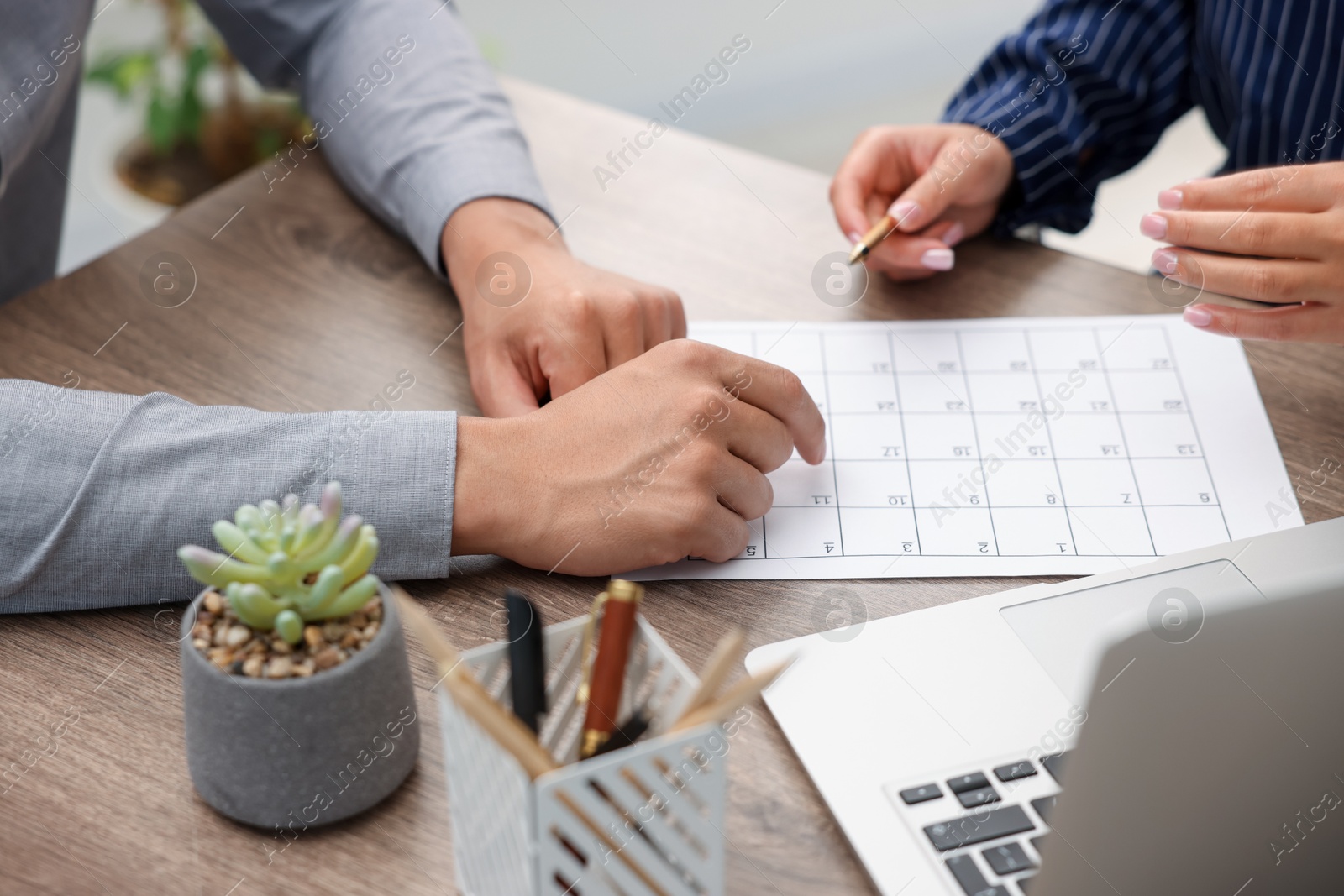 Photo of Woman and man using business planner at wooden desk, closeup