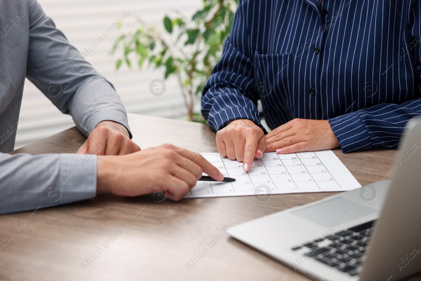 Photo of Woman and man using business planner at wooden desk, closeup
