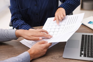 Photo of Woman and man using business planner at wooden desk, closeup