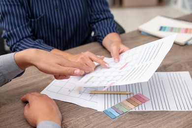 Photo of Woman and man using business planner at wooden desk, closeup
