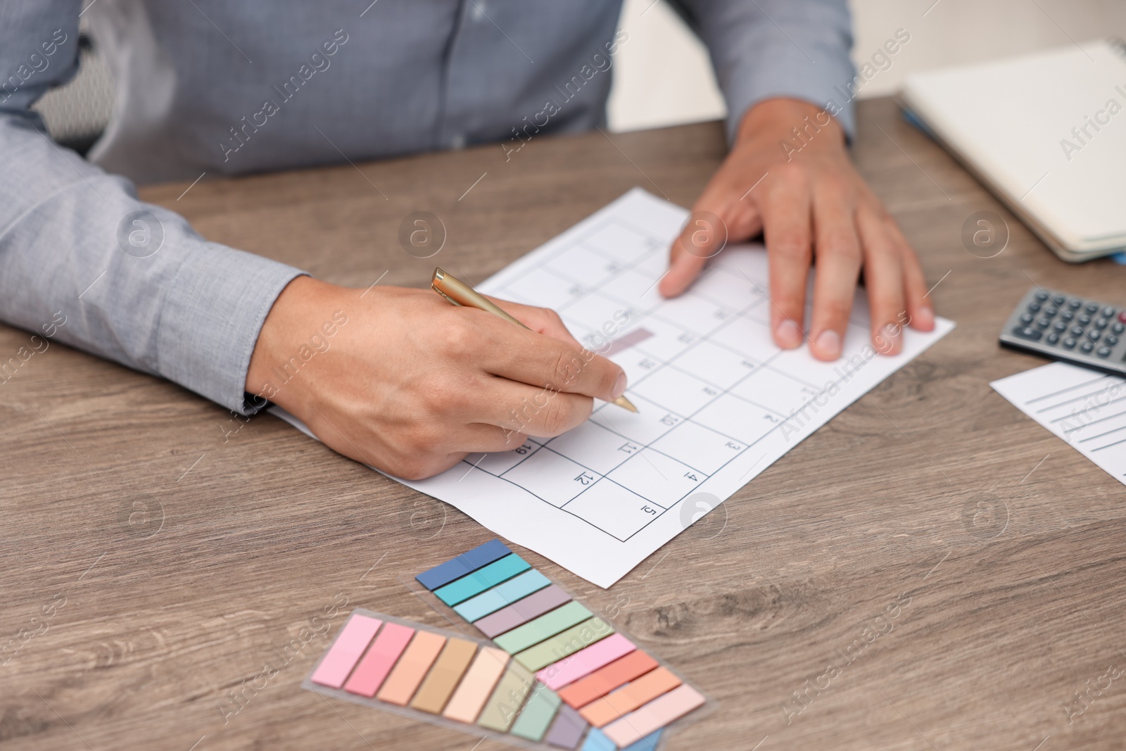 Photo of Man using business planner at wooden desk, closeup