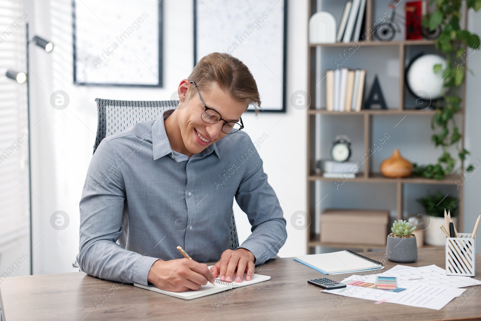 Photo of Man writing in planner at wooden table indoors