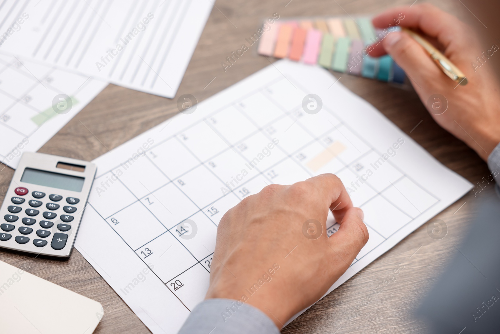 Photo of Man using business planner at wooden desk, closeup