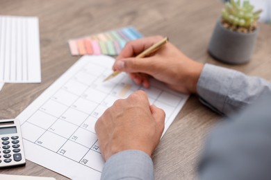 Photo of Man using business planner at wooden desk, closeup