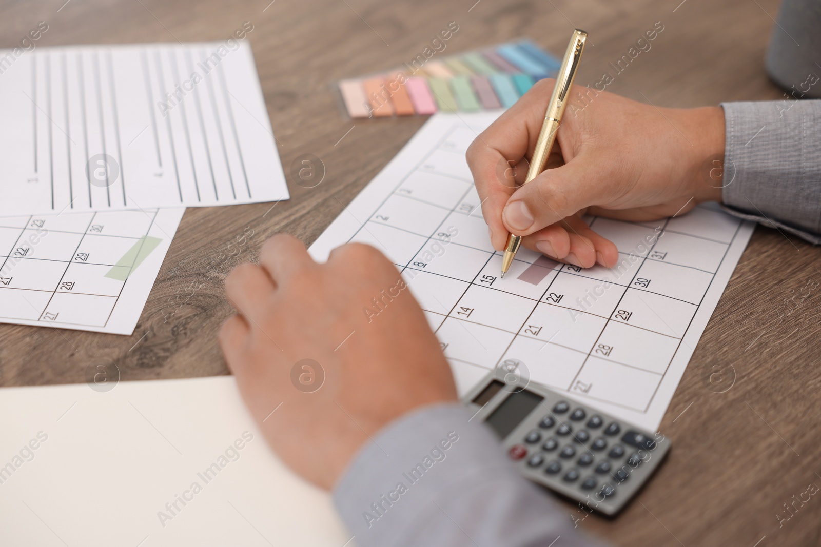 Photo of Man using business planner at wooden desk, closeup