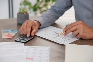 Photo of Man using business planner and calculator at wooden desk, closeup