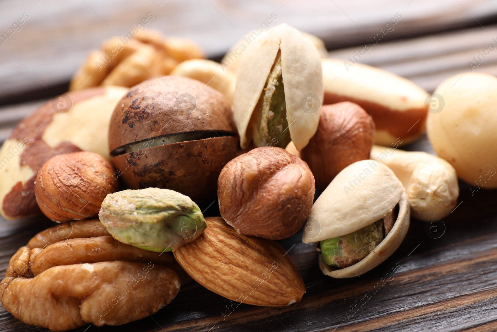 Photo of Mix of different nuts on wooden table, closeup