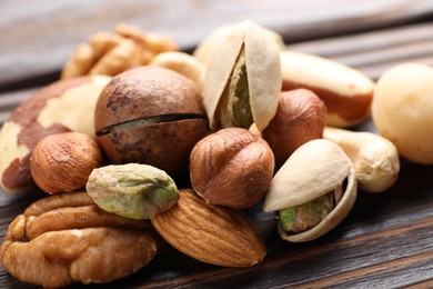 Photo of Mix of different nuts on wooden table, closeup