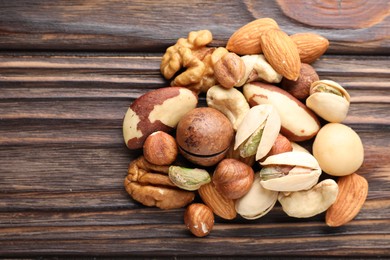 Photo of Mix of different nuts on wooden table, top view. Space for text