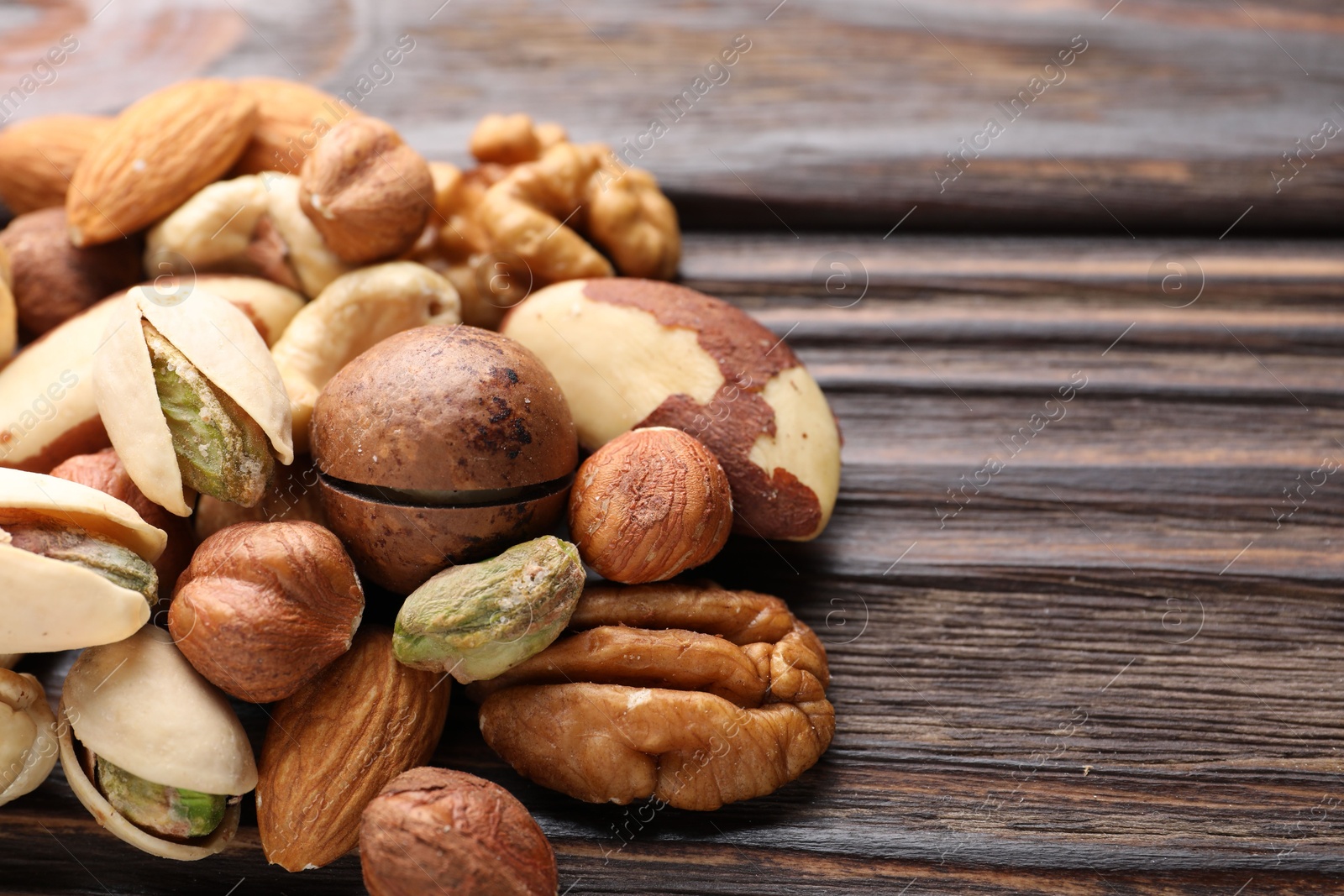 Photo of Mix of different nuts on wooden table, closeup. Space for text