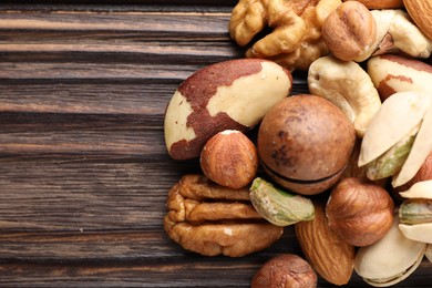 Photo of Mix of different nuts on wooden table, closeup. Space for text
