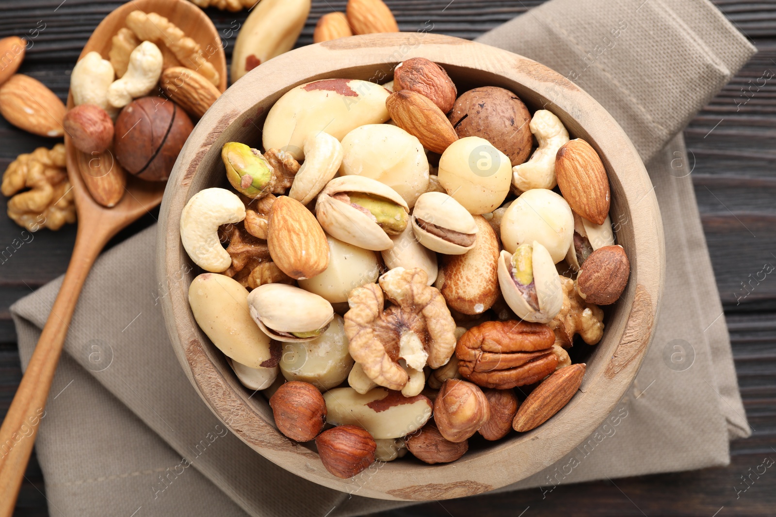 Mix of different nuts in bowl and spoon on wooden table, flat lay Photo of Mix of different nuts in bowl and spoon on wooden table, flat lay
