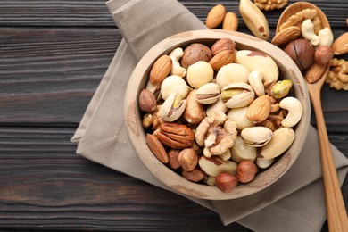 Photo of Mix of different nuts in bowl and spoon on wooden table, flat lay. Space for text