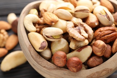 Photo of Mix of different nuts in bowl on table, closeup
