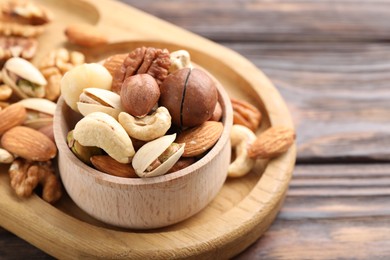 Photo of Mix of different nuts on wooden table, closeup