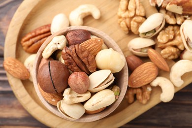 Photo of Mix of different nuts on wooden table, top view