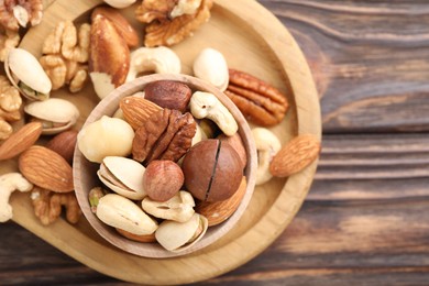 Photo of Mix of different nuts on wooden table, top view. Space for text