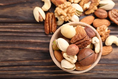 Photo of Mix of different nuts on wooden table, flat lay. Space for text