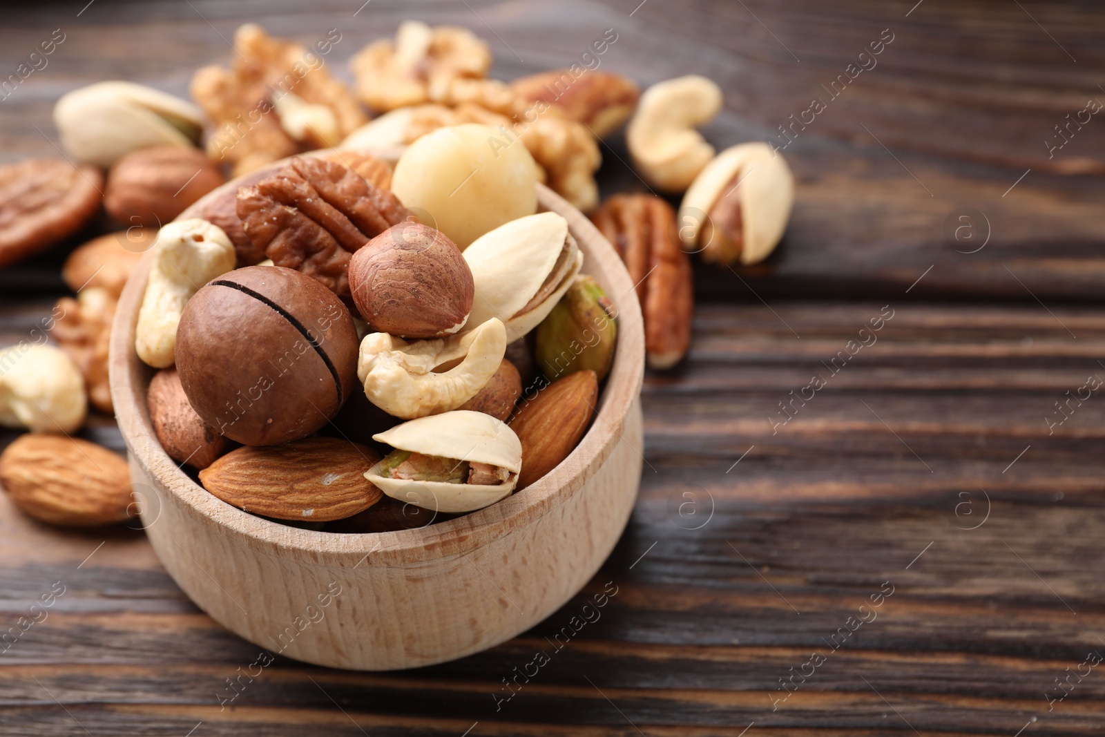 Photo of Mix of different nuts on wooden table, closeup. Space for text