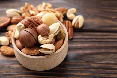 Photo of Mix of different nuts on wooden table, closeup. Space for text