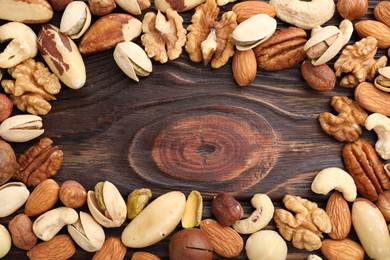 Photo of Mix of different nuts on wooden table, flat lay. Space for text