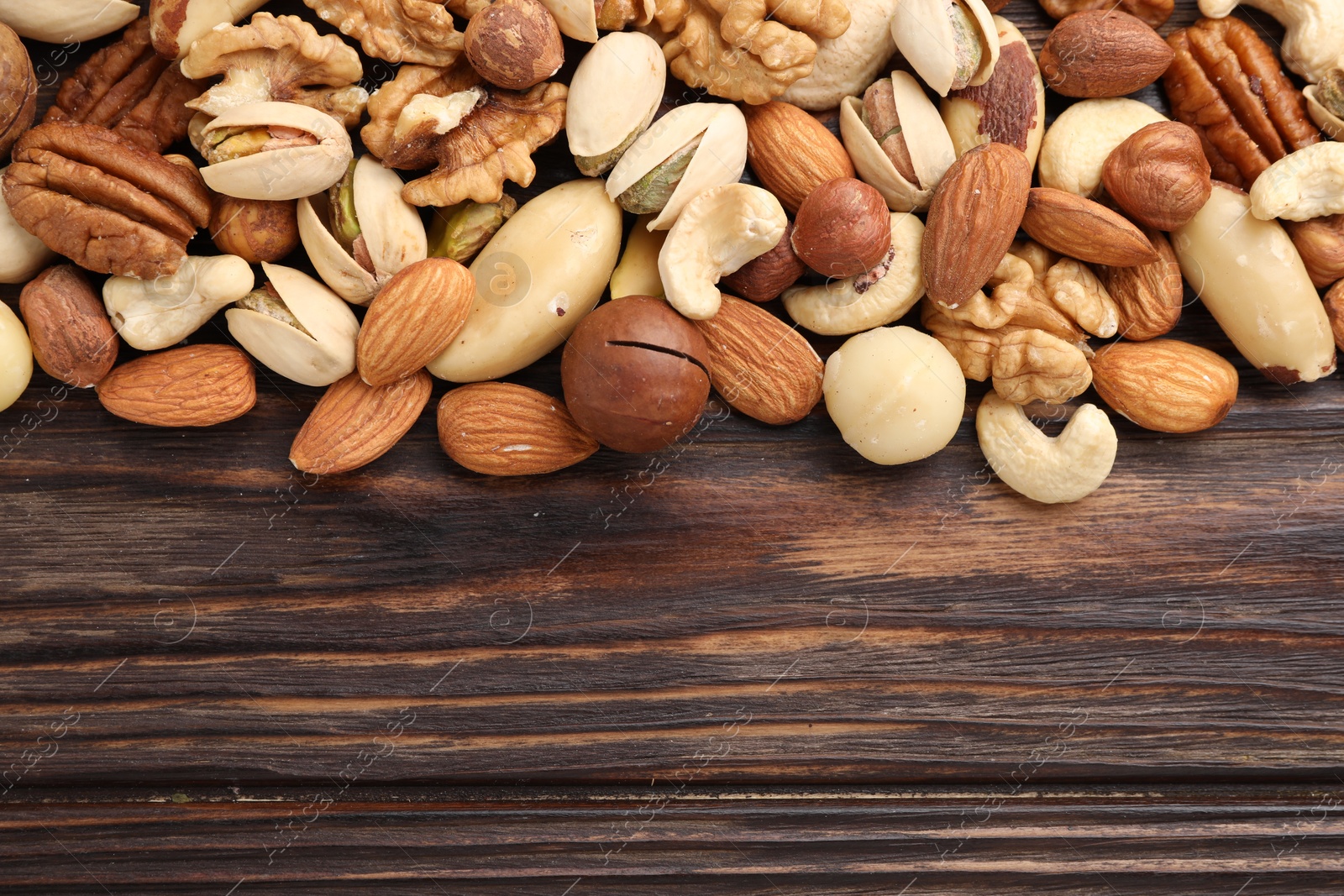 Photo of Mix of different nuts on wooden table, flat lay. Space for text