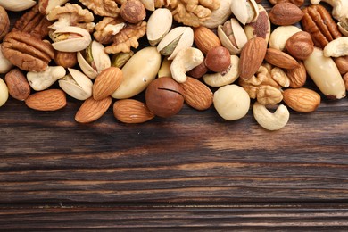Photo of Mix of different nuts on wooden table, flat lay. Space for text