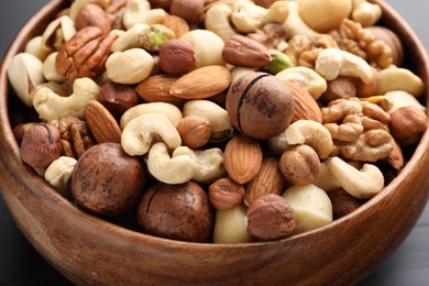 Photo of Mix of different nuts in bowl on table, closeup