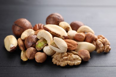 Photo of Mix of different nuts on black wooden table, closeup