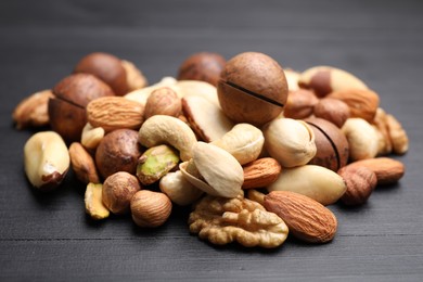 Photo of Mix of different nuts on black wooden table, closeup