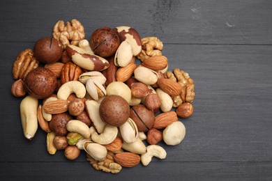 Photo of Mix of different nuts on black wooden table, flat lay. Space for text