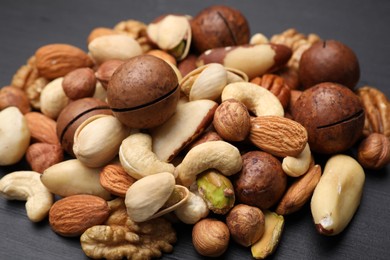 Photo of Mix of different nuts on black wooden table, closeup