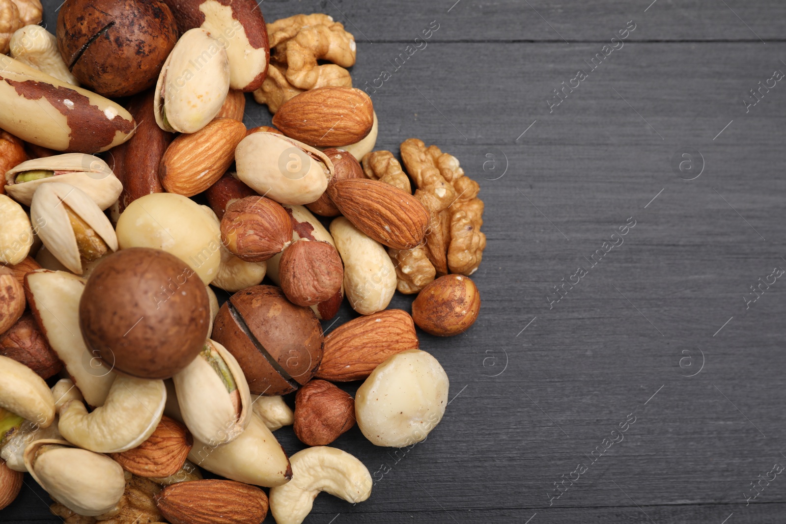 Photo of Mix of different nuts on black wooden table, flat lay. Space for text