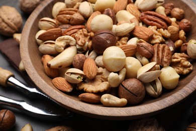 Photo of Mix of different nuts in bowl and nutcracker on table, closeup