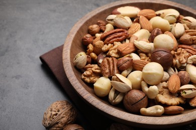 Photo of Mix of different nuts in bowl on grey table, closeup. Space for text