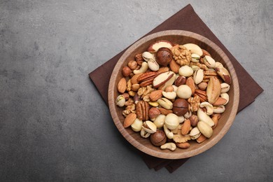 Photo of Mix of different nuts in bowl on grey table, top view. Space for text