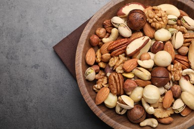 Photo of Mix of different nuts in bowl on grey table, top view. Space for text