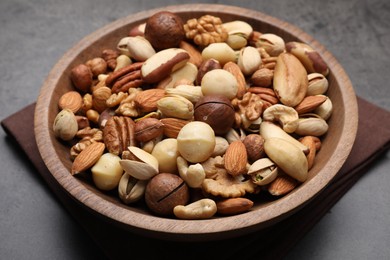 Photo of Mix of different nuts in bowl on grey table, closeup