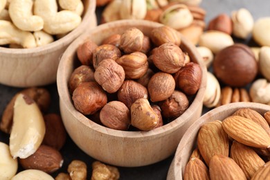 Photo of Mix of different nuts in bowls on table, closeup