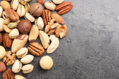 Photo of Mix of different nuts on grey table, flat lay. Space for text
