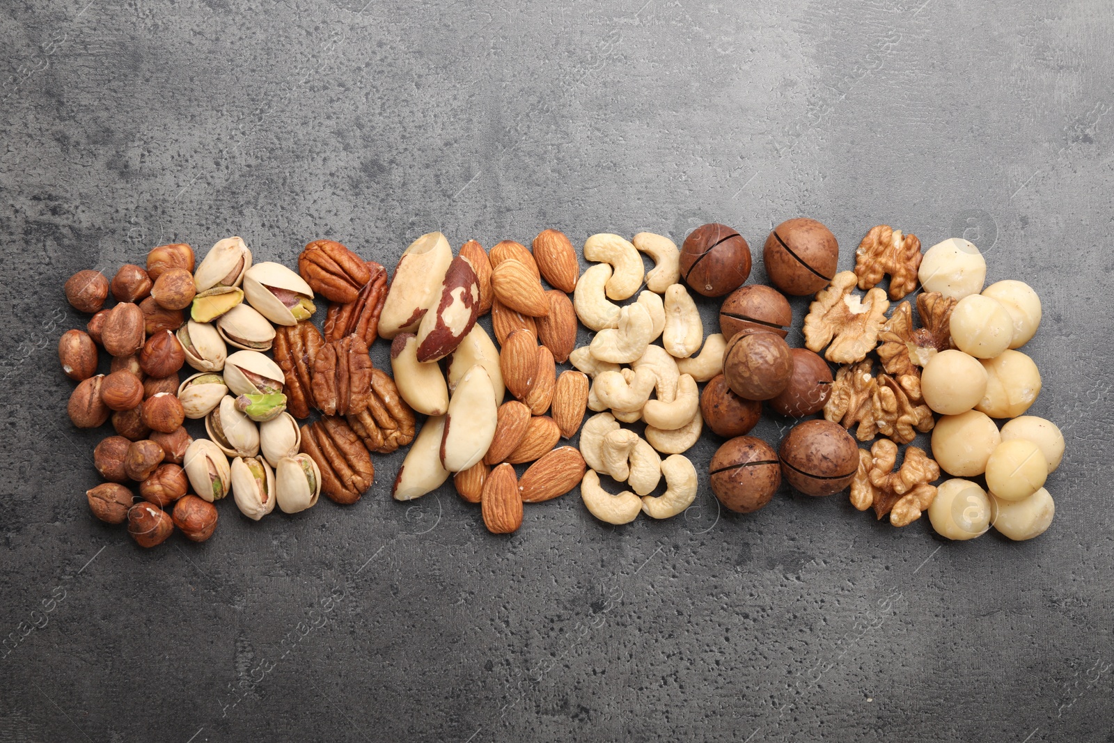 Photo of Mix of different nuts on grey table, flat lay