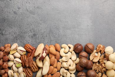 Photo of Mix of different nuts on grey table, flat lay. Space for text